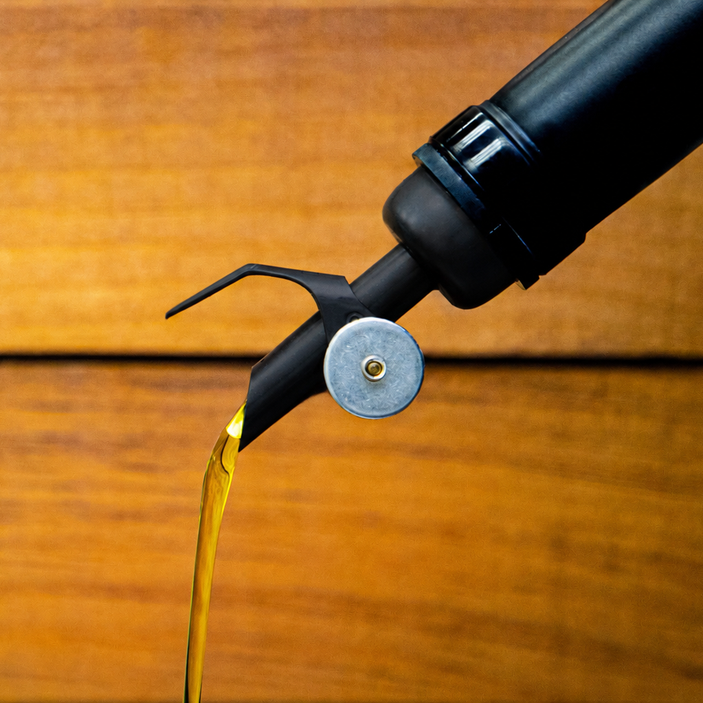 Black pour spout with fresh olive oil coming out.