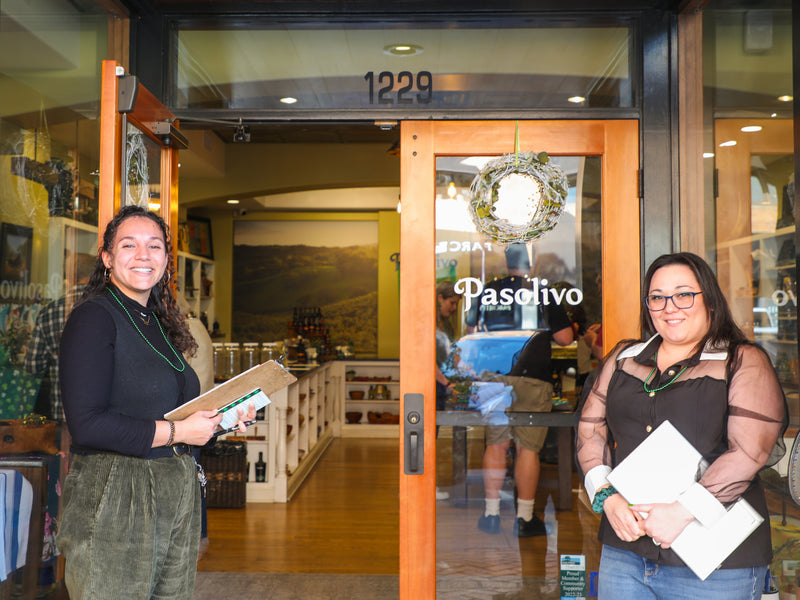 Two women standing outside a building with 'Pasolivo' on the door.