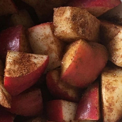 Close-up of diced red apples coated with cinnamon and other spices, filling the frame.